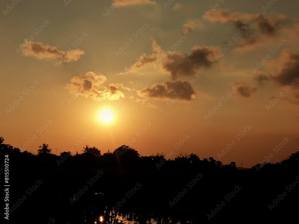 sunset over the rice fields. tree shadows and the orange light of the sun in the afternoon. a bunch of clouds hung in the evening sky. nature painting. natural orange and black. sunset over the rice fields. tree shadows and the orange light of the sun in the afternoon. a bunch of clouds hung in the evening sky. nature painting. natural orange and black.