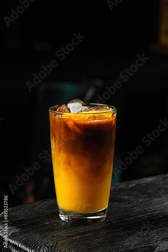 Fotografía A glass of refreshing iced bumble cold coffee drink with orange juice, on wooden