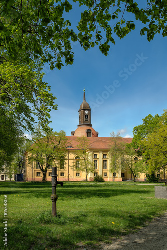 Blick von Südosten auf die Fassade der denkmalgeschützten Kulturkirche St. Marien in Neuruppin im Frühling, im Vordergrund eine historische Wasserpumpe photo