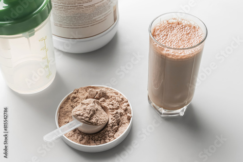 Protein drink cocktail in a glass and whey protein powder in a measuring scoop