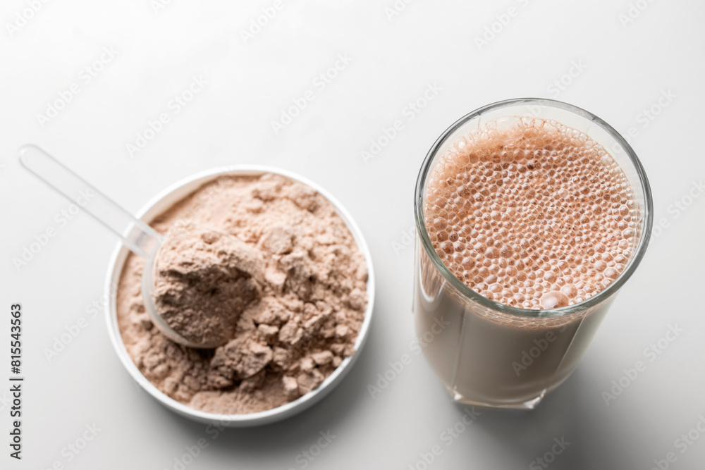 Protein drink cocktail in a glass and whey protein powder in a measuring scoop Protein drink cocktail in a glass and whey protein powder in a measuring scoop