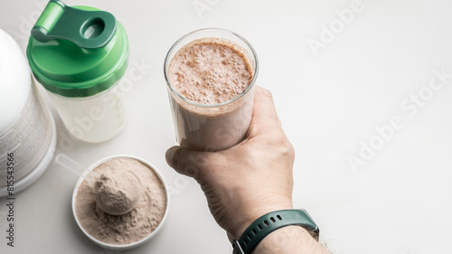 Male hand holding a protein drink cocktail in a glass