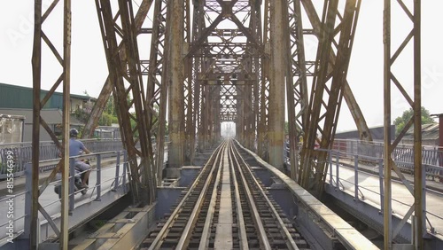 Vintage steel train bridge at Long Bien railway through a river in Downtown Hanoi, Vietnam. Urban city town.