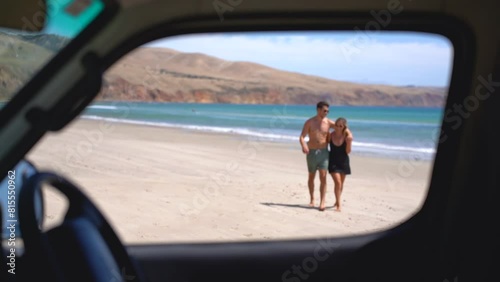 A couple walking and laughing on the beach. They start out of focus but slowly walk into focus as they get nearer to the camera. This is shot through the front seat of a van on the beach in Australia. photo