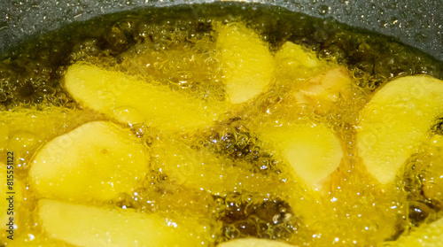 Primer plano de patatas friéndose en aceite caliente. Trozos de patatas rodeadas de burbujas del aceite hirviendo en su proceso de elaboración. French fries.