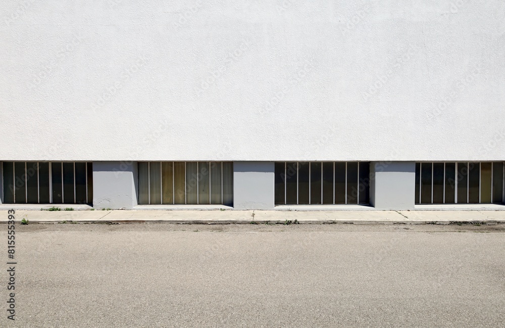 Barred basement windows on white plaster wall of residential building at the roadside . Concrete sidewalk and road in front. Background for copy space. Barred basement windows on white plaster wall of residential building at the roadside . Concrete sidewalk and road in front. Background for copy space.