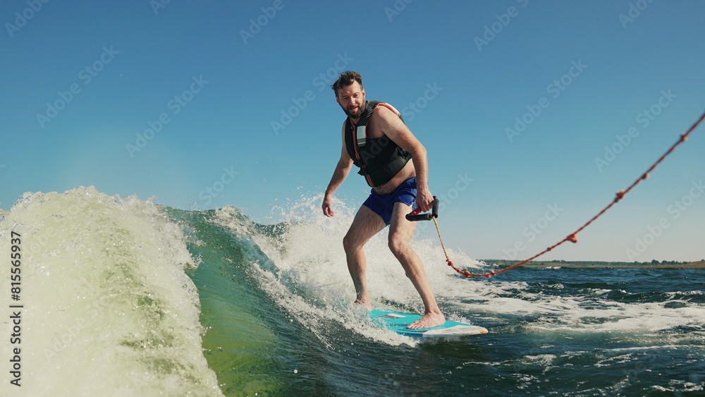 A man wakeboards after a boat. Fun on the water during the hot summer on the lake. Wakeboarding. Summer sports on a lake with blue water. Wakeboarding behind a motor boat. Active lifestyle concept. A man wakeboards after a boat. Fun on the water during the hot summer on the lake. Wakeboarding. Summer sports on a lake with blue water. Wakeboarding behind a motor boat. Active lifestyle concept.