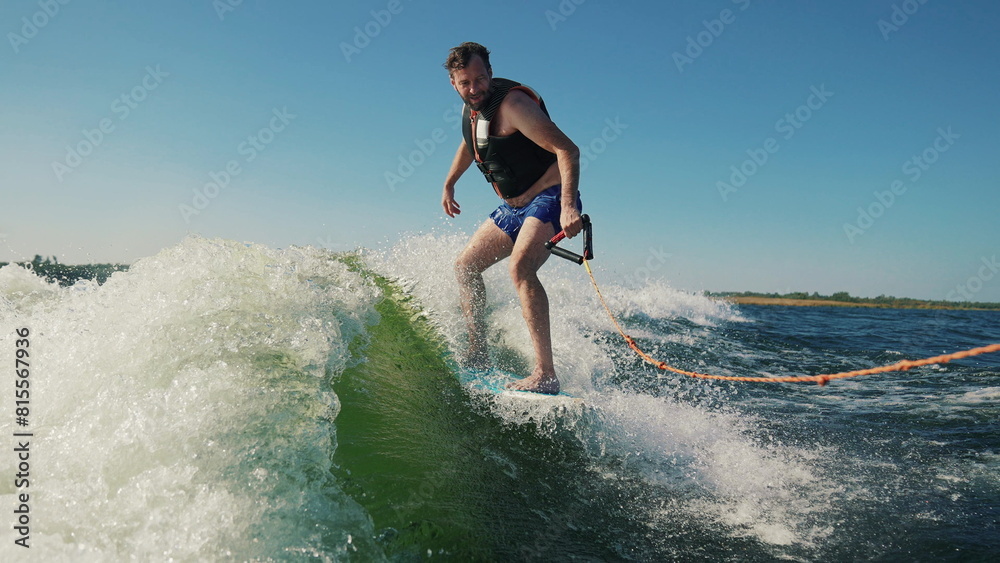 A man wakeboards after a boat. Fun on the water during the hot summer on the lake. Wakeboarding. Summer sports on a lake with blue water. Wakeboarding behind a motor boat. Active lifestyle concept.