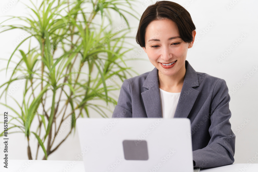 ビジネススーツを着てラップトップを操作している若い女性 ビジネスイメージ ビジネススーツを着てラップトップを操作している若い女性 ビジネスイメージ