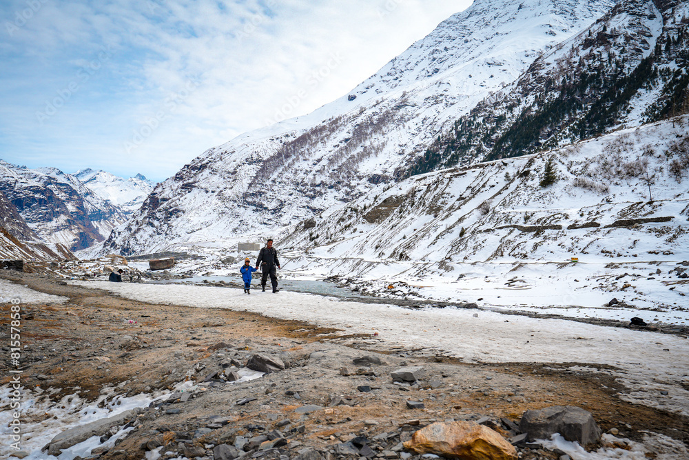 High-resolution stock photos of a father and son hiking in the snow-covered mountains near Rohtang Pass, at the entrance of Atal Tunnel, with a picturesque lake backdrop in Solang Valley, Himachal 