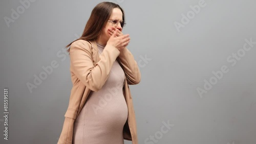 Sick pregnant woman wearing dress jacket and glasses isolated over gray background feeling toxicosis suffering vomit covering her mouth with hands feeling unwell during pregnancy photo