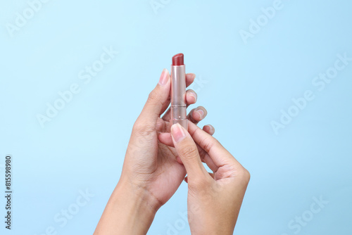 Woman hands hold red lipstick isolated on blue background
