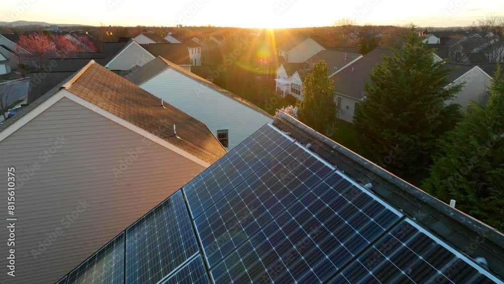 Solar panels during golden hour sunset. Close-up aerial flyover towards sunburst. Eco-friendly, clean energy generate on suburban home in USA.