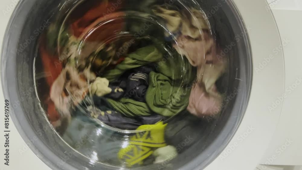 Clothes are washed in a washing machine. The process of washing things in a washing machine. Clothes spinning in the washing machine.