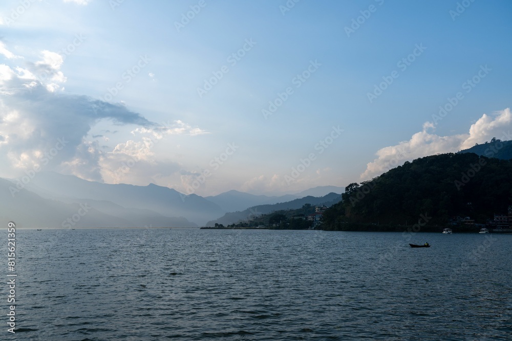 Small boat sailing in the middle of a vast lake surrounded by majestic mountains. Small boat sailing in the middle of a vast lake surrounded by majestic mountains.