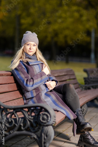 Young Woman In Park At Autumn Season Happy Free Natural Portrait Girl Breathing Deeply in Coat Sitting on Bench On Foliage in Background As Pretty Woman Expressing Outdoor.