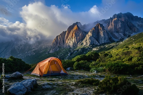 Tent set up in a tranquil mountainous area as the last sunlight kisses the peaks