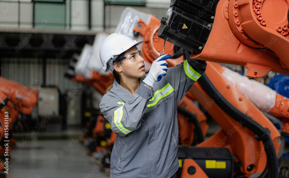 Industrial engineer working on robot maintenance in AI futuristic electronic technology factory. Female technician checking automated robotic machine. Modern smart woman empowerment in industry 4.0.