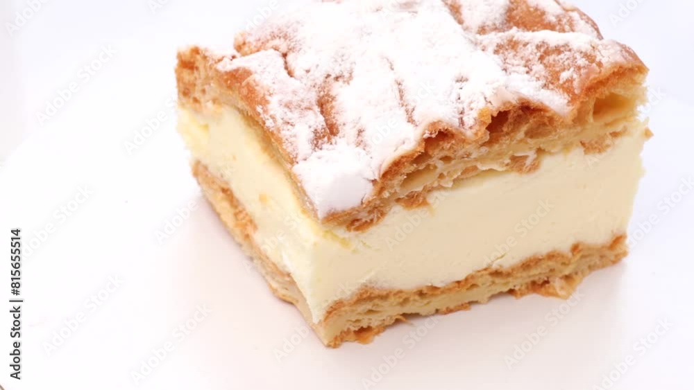 Polish traditional Carpathian cake, rotation in circle. a piece of cake, Turning. Cake made of choux pastry dough and custard cream, topped with powdered sugar. Polish traditional Carpathian cake, rotation in circle. a piece of cake, Turning. Cake made of choux pastry dough and custard cream, topped with powdered sugar.