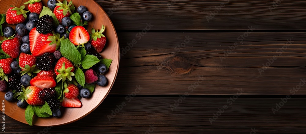 A plate of fresh berry salad is presented on a wooden background with a top view angle for a flat lay image Ample copy space is available A plate of fresh berry salad is presented on a wooden background with a top view angle for a flat lay image Ample copy space is available