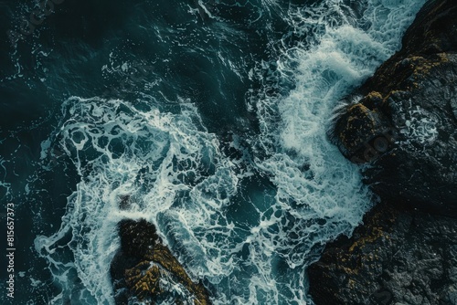 Aerial view of foamy ocean waves splashing against rocks