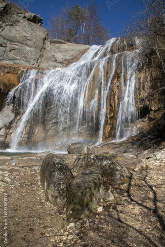 a waterfall in the woods with two rocks and a rock bench photo