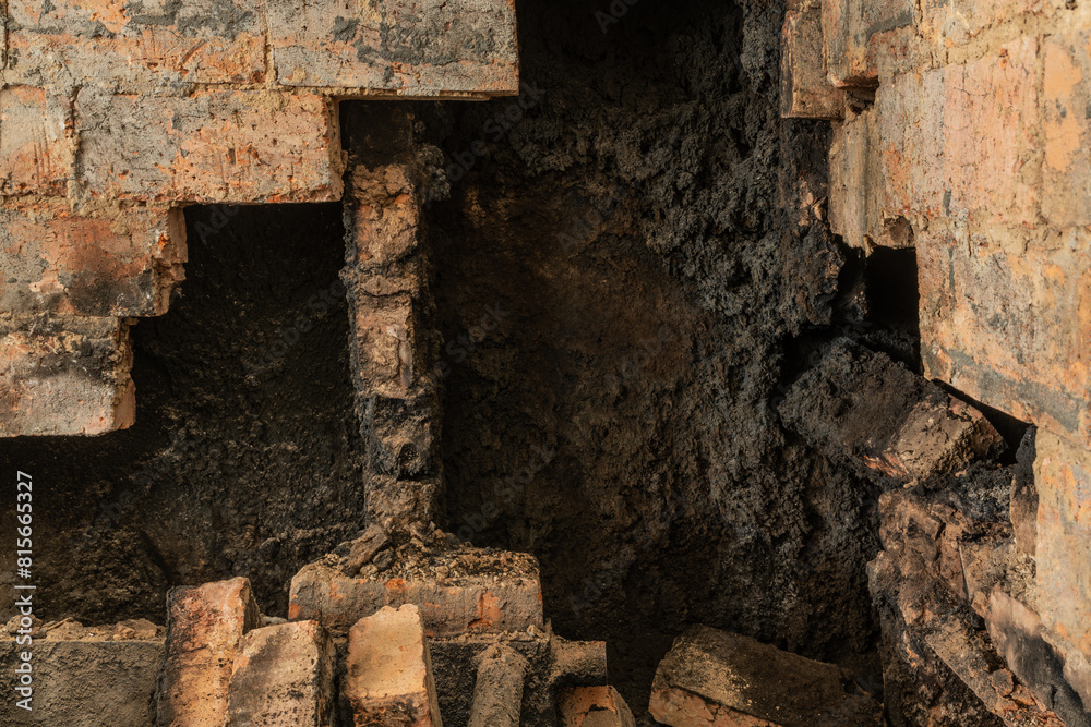 Dismantling an old brick oven. Black soot inside the furnace wells. Dirty and dusty work during house renovation. Concept of destruction after a fire.