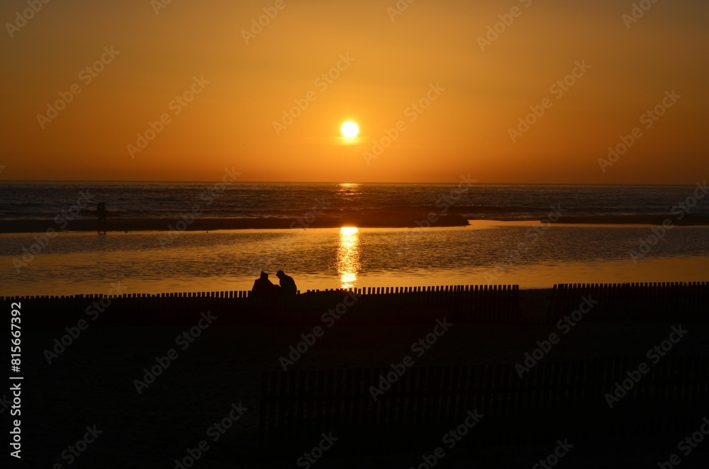 Obraz premium Picturesque scene of a waterfront park at sunset with a family seated on a bench enjoying the view