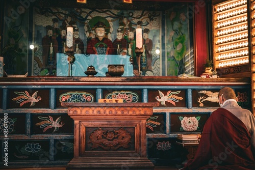 Buddhist monk in traditional saffron robes are seen in a shrine, bowing in prayer and contemplation