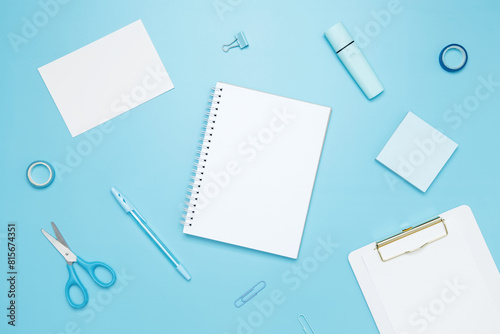 Creative flat lay mockup design of workspace. Top view composition with white notebook, to do list and stationery on blue background