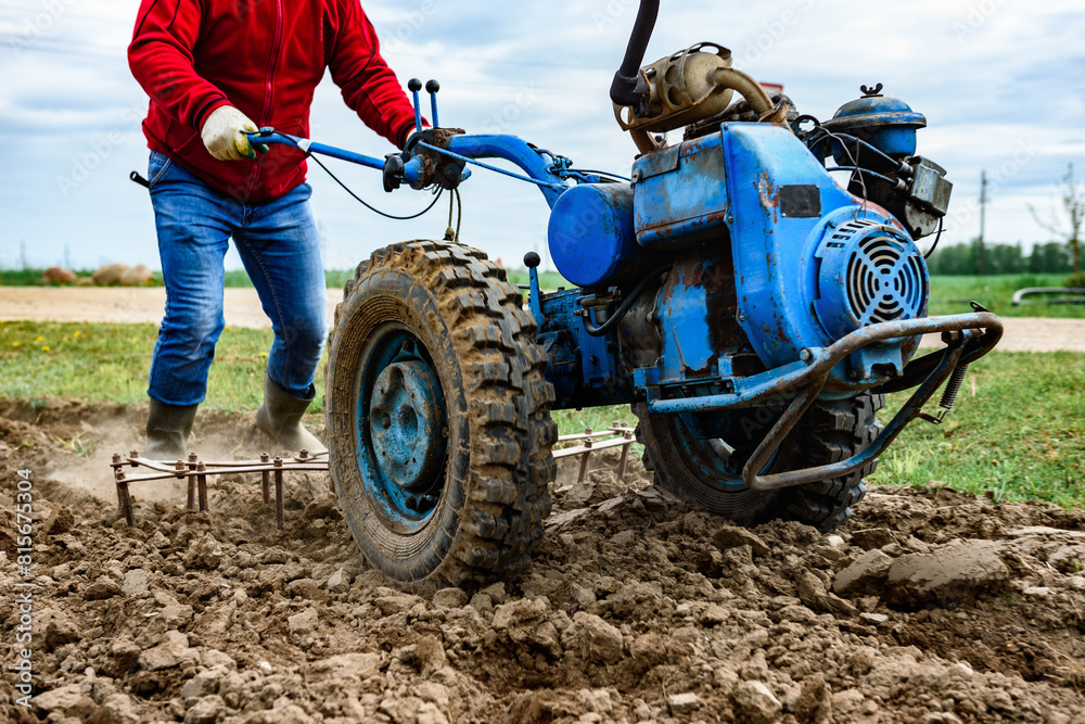 Man cultivating soil with tiller block in spring.