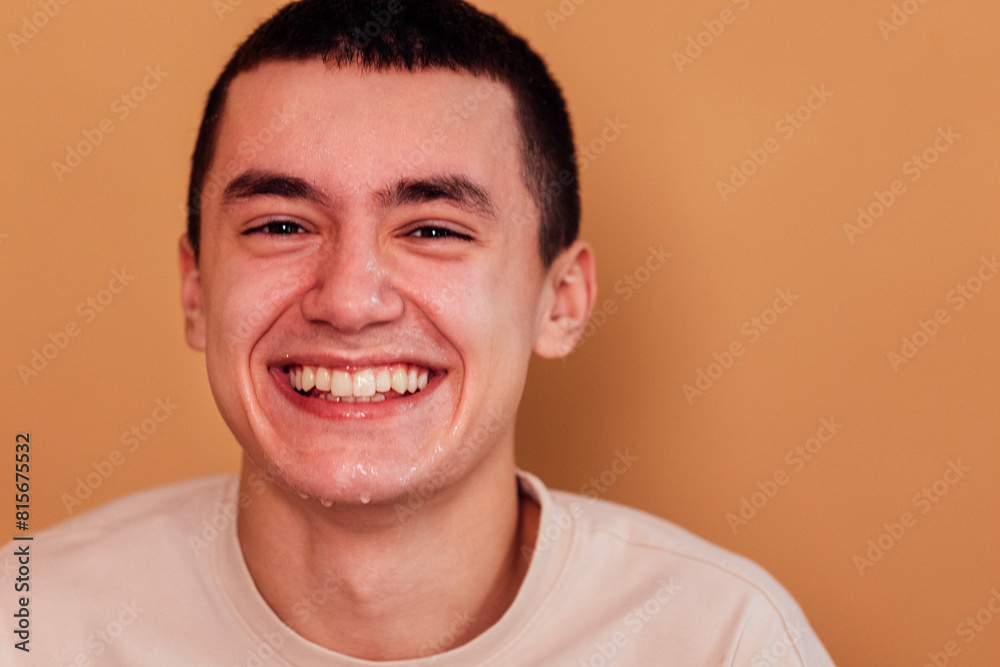 Portrait of young man is standing against light wall and washing his face in the morning Portrait of young man is standing against light wall and washing his face in the morning