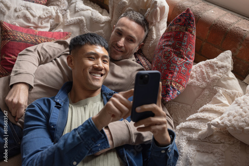 Gay couple relaxing on vacation looking at a smartphone together photo