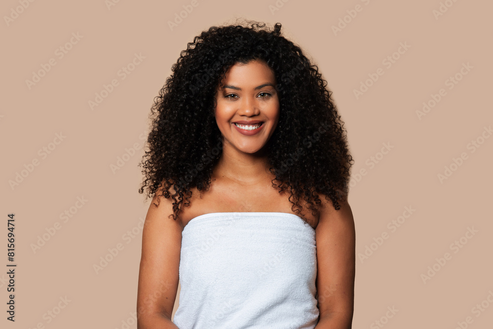 A young woman with curly hair stands wrapped in a white towel, her hair wet and dripping slightly. She looks directly at the camera, with a neutral expression, in a simple and unadorned setting. A young woman with curly hair stands wrapped in a white towel, her hair wet and dripping slightly. She looks directly at the camera, with a neutral expression, in a simple and unadorned setting.