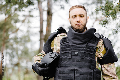 Young soldier in uniforms and tactical vest works in the forest and prepares for action at a temporary forest base. A man does in the work of demining the territory