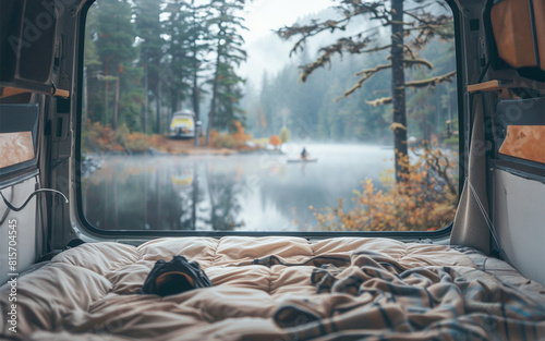 View from inside bed of a camper van to an idyllic lake and forest scenery outside. Vacation or camping in a motor home concept