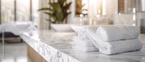 A neatly stacked set of fresh towels await guests in a luxurious, sunlit bathroom.