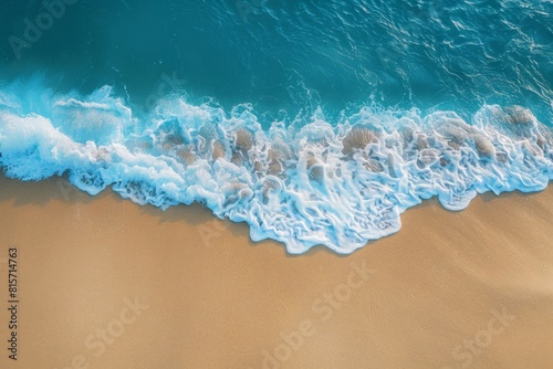 Soft blue ocean wave on clean sandy beach background.