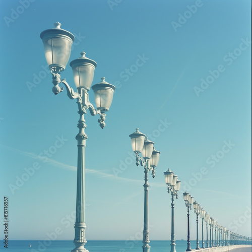 A lineup of beach promenade street lamps stands tall under a pristine blue sky.