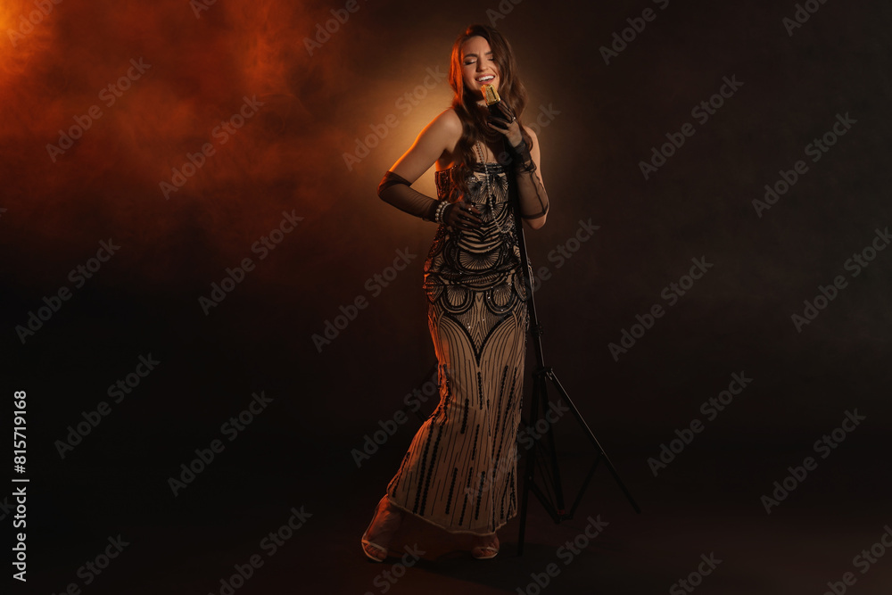 Beautiful young woman with microphone singing in color lights and smoke Beautiful young woman with microphone singing in color lights and smoke