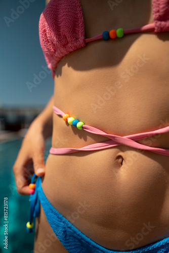 A fashionable and sophisticated woman relaxes by the pool, dressed in a blue bikini.