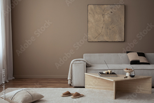 Warm and cozy living room interior with mock up poster frame, painting, beige sofa, travertine coffee table, slippers, bowl with nuts, plaid, pillow and personal accessories. Home decor. Template. © FollowTheFlow