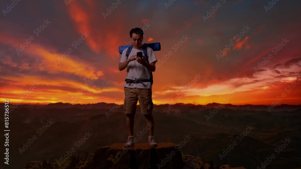 Full Body Of Asian Male Hiker With Mountaineering Backpack Looking At The Smartphone And Screaming Goal Celebrating The Success While Standing On Top Mountain During Sunset Time Full Body Of Asian Male Hiker With Mountaineering Backpack Looking At The Smartphone And Screaming Goal Celebrating The Success While Standing On Top Mountain During Sunset Time