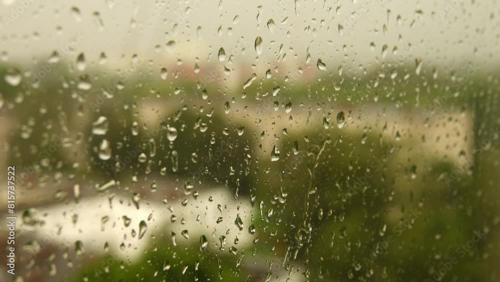 Drops of water flowing down glass during heavy rain. Cloudy summer weather. In background of city view. Drops of water flowing down glass during heavy rain. Cloudy summer weather. In background of city view.