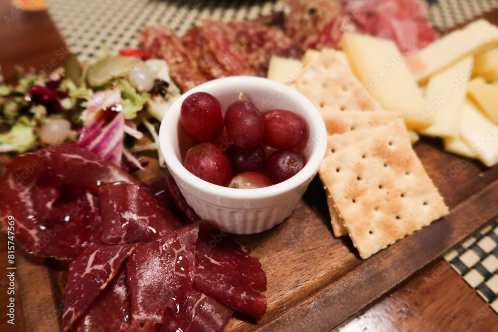 close up of cheese, ham, grape, raisin, biscuit, olive and salad platter on a wooden plate close up of cheese, ham, grape, raisin, biscuit, olive and salad platter on a wooden plate
