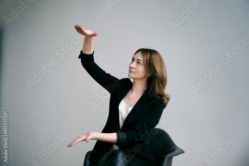 young woman in a black jacket spreads her hands showing the size