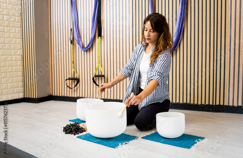 An adult woman performs a sound bath session with quartz bowls inside a room.Concept of sound therapy. Vibrational Therapy that uses the effect of sound.