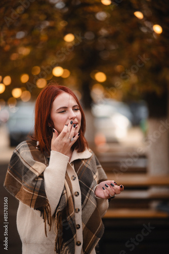 A merry red-haired girl radiates happiness as she walks through the autumn city streets.