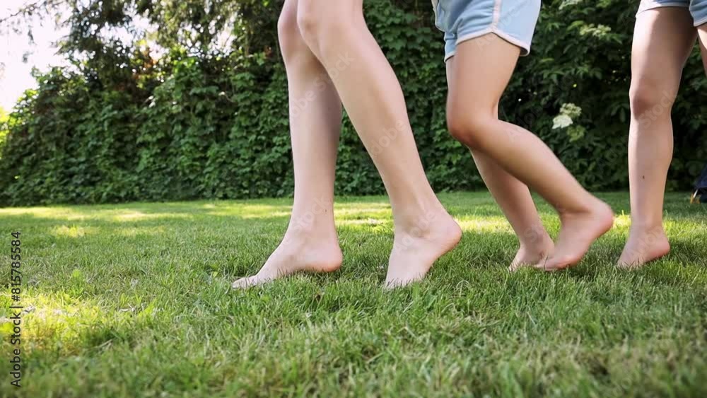 Children run barefoot on green grass in the park. children follow each other in nature. Summer picnic, healthy lifestyle. Children's feet in the park on the grass.