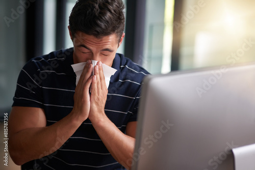 Sick, tissue and business man blowing nose at desk for sneeze, virus infection or flu bacteria. Lens flare, scriptwriter and employee in office with computer for disease, congestion or hay fever photo